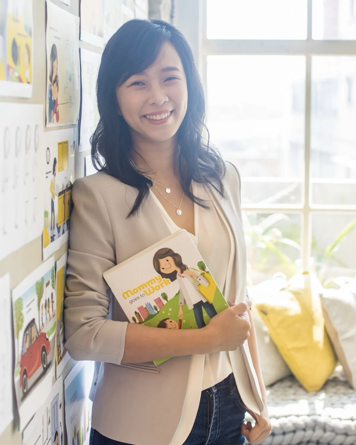 Jossy Lee holding the first edition, in front of the wall of storyboard sketches