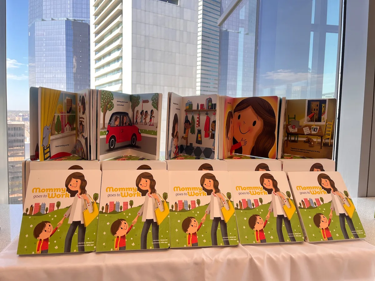 Rows of Mommy Goes to Work books on a table by an office window