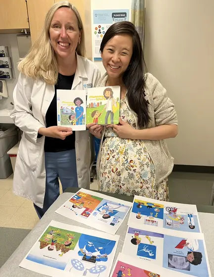 A doctor in a white coat and Jossy Lee with the book over its printed spreads