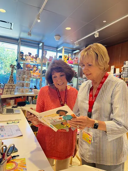 Two hospital gift shop volunteers reading the book