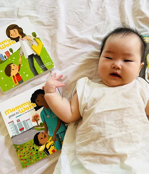 A baby lying next to the books