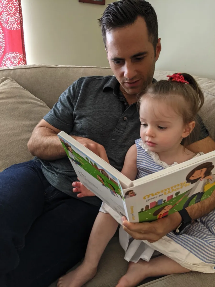 A dad reading to his daughter on the sofa