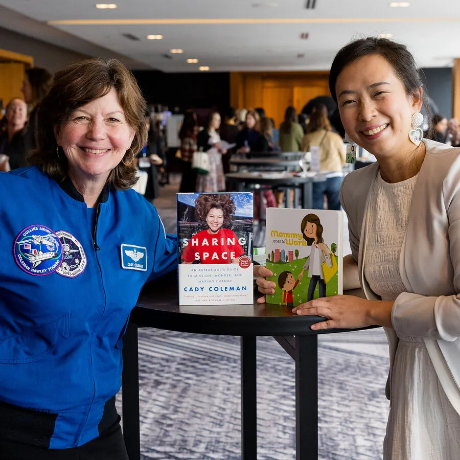 Astronaut Cady Coleman and Jossy Lee, each holding the other's book