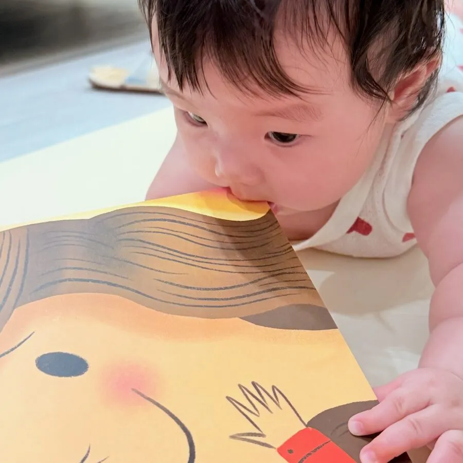 A baby leaning over an open page of the book