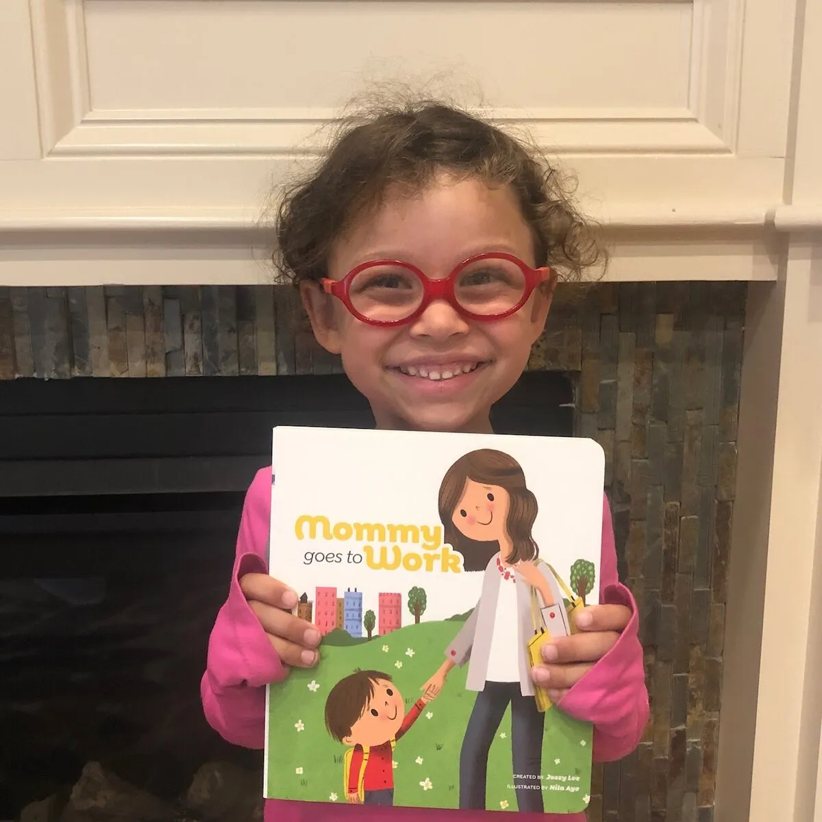 A girl in red glasses holding the book up to the camera