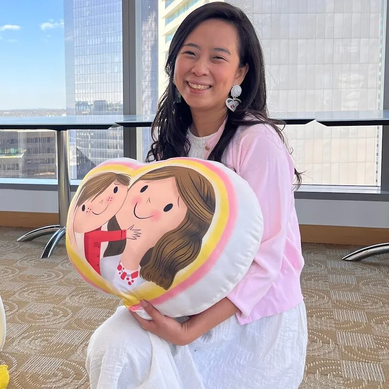 Jossy Lee holding the heart cushion from the book, at an event high above Boston
